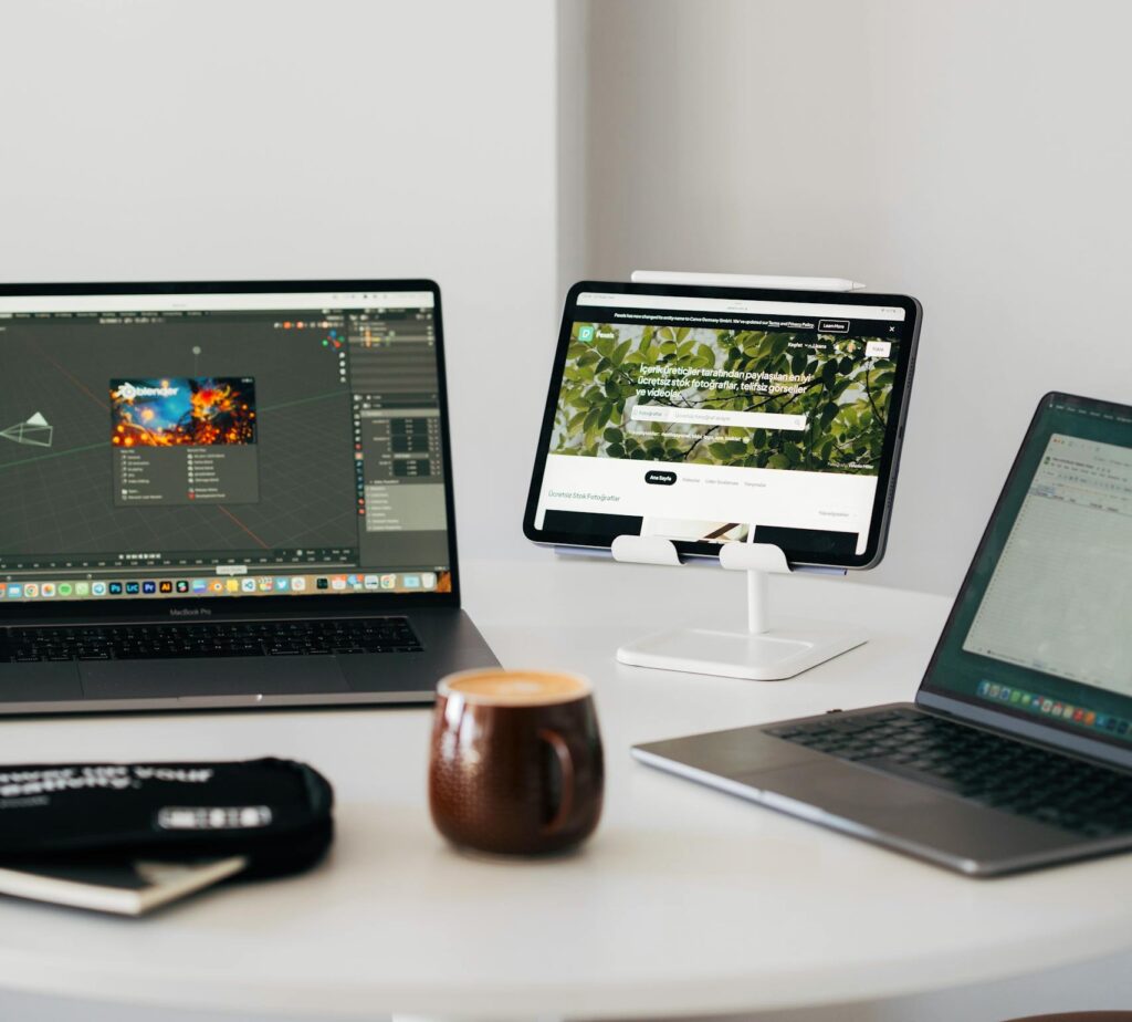 Efficient remote workspace featuring dual laptops, tablet, and coffee mug on a desk.